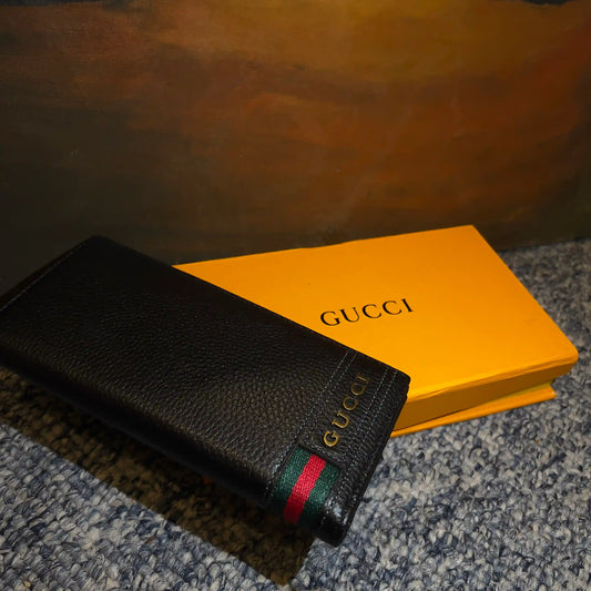 Black Gucci wallet with a red and green stripe on a yellow Gucci box.